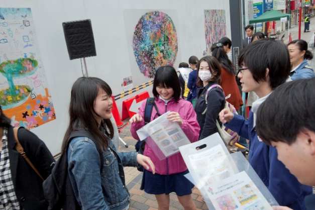 アート作品がプリントされた記念品を手に喜ぶ製作者